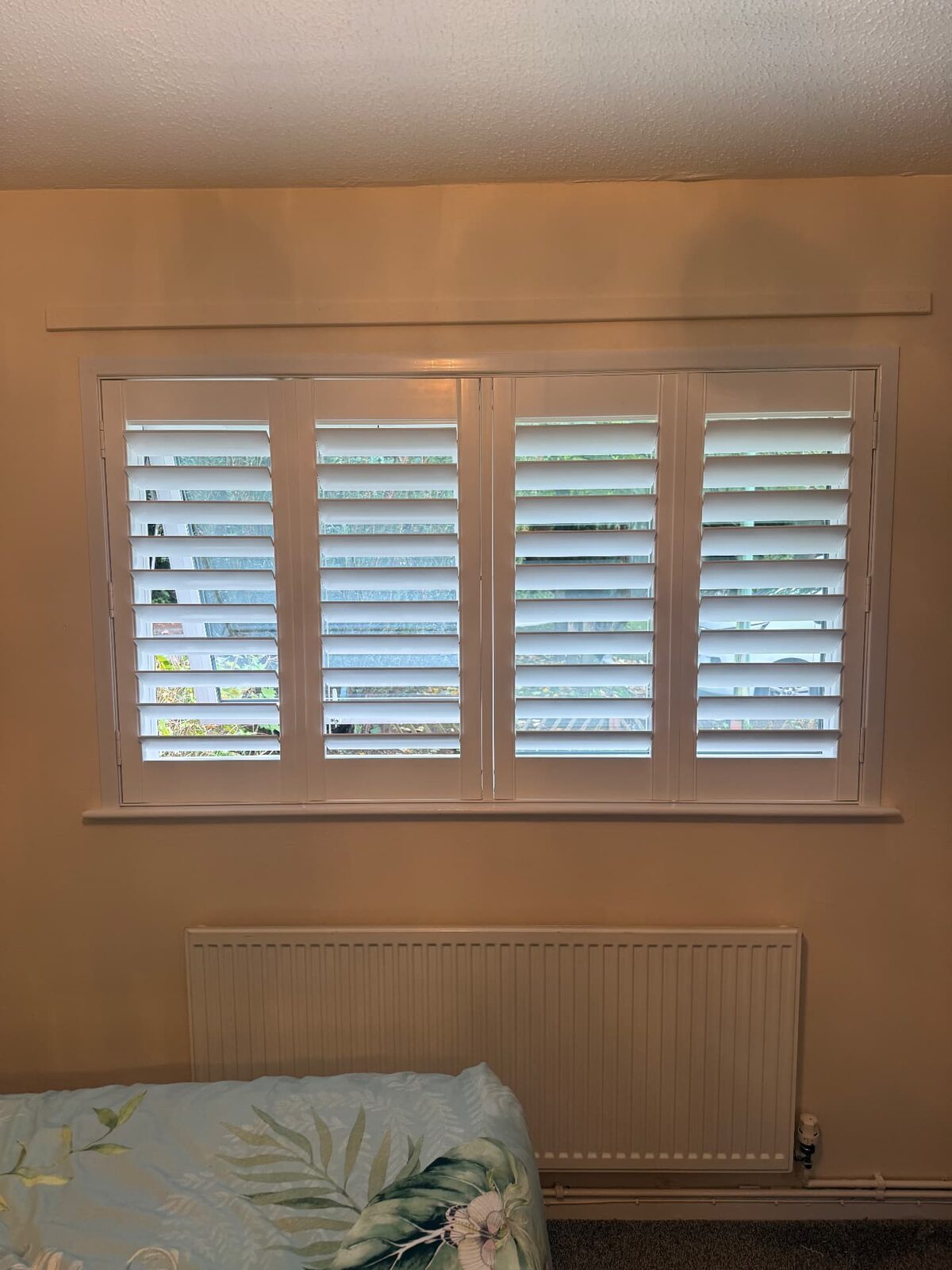 Cream full-height plantation shutters fitted by The Welsh Shutter Company in a bedroom